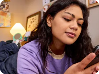 Woman laughing looking at mobile device while chatting on WhatsApp