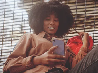 woman laughing looking at mobile device while chatting on whatsapp